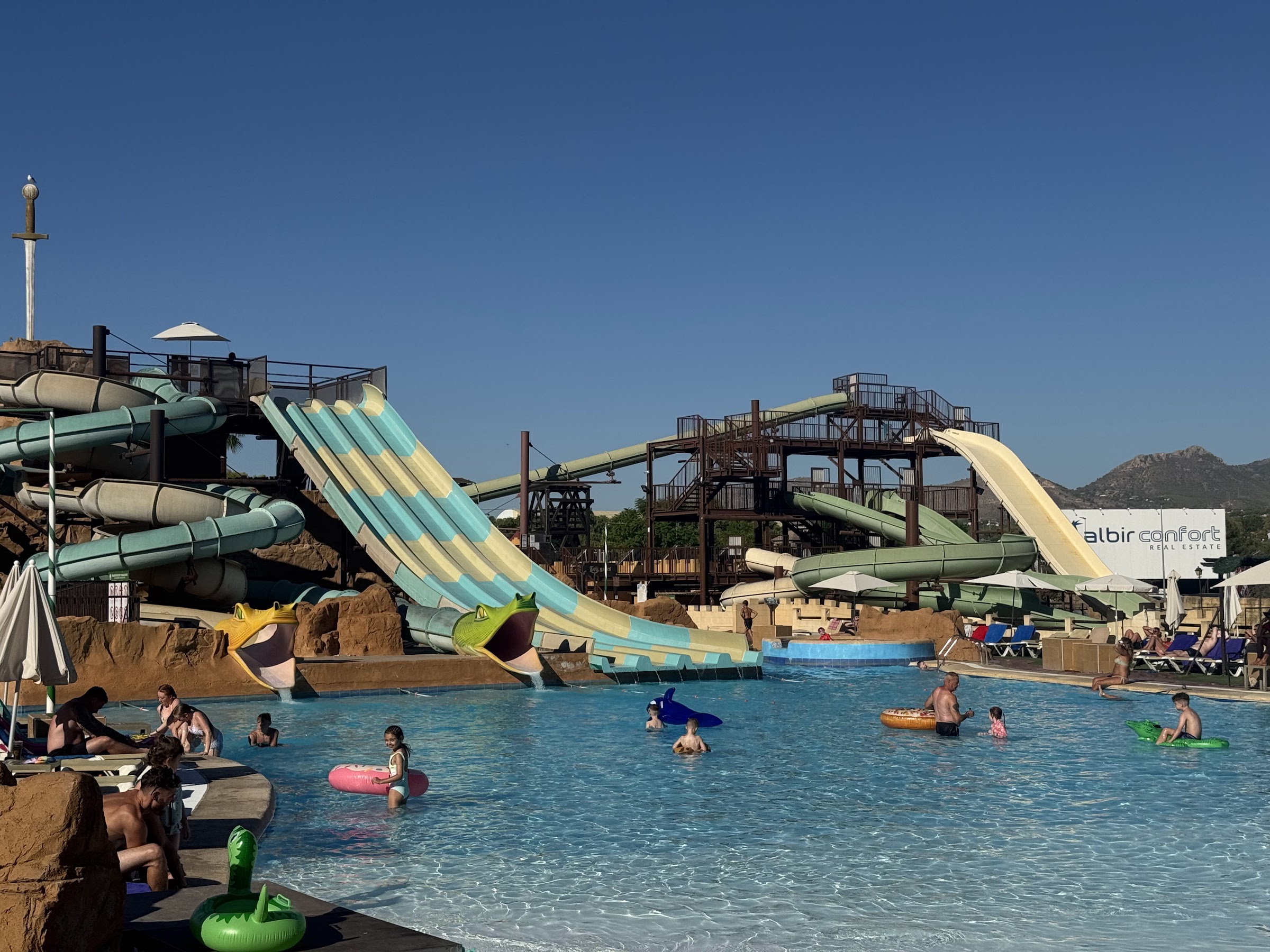 Toboganes de colores y piscina con niños y flotadores en el parque acuático del Magic Robin Hood Resort
