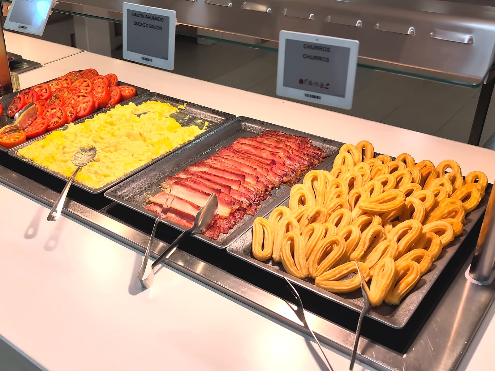 El desayuno caliente del Mediterráneo Bay: churros, beicon, huevos revueltos y tomate
