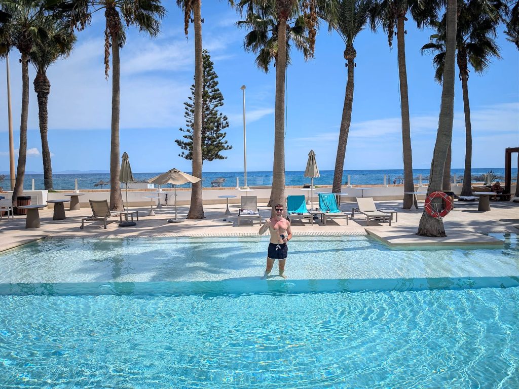 Javier Sobrino en la piscina del Mediterráneo Bay, entre palmeras y con el mar detrás