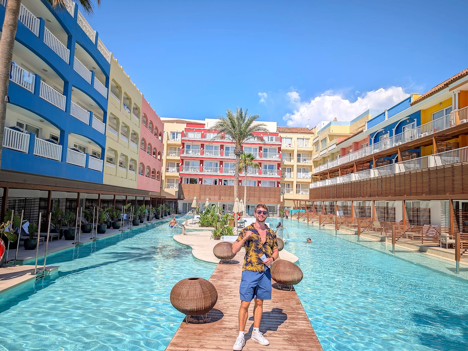 Javier Sobrino en la pasarela de madera de la piscina alargada del Mediterráneo Bay, entre edificios de colores