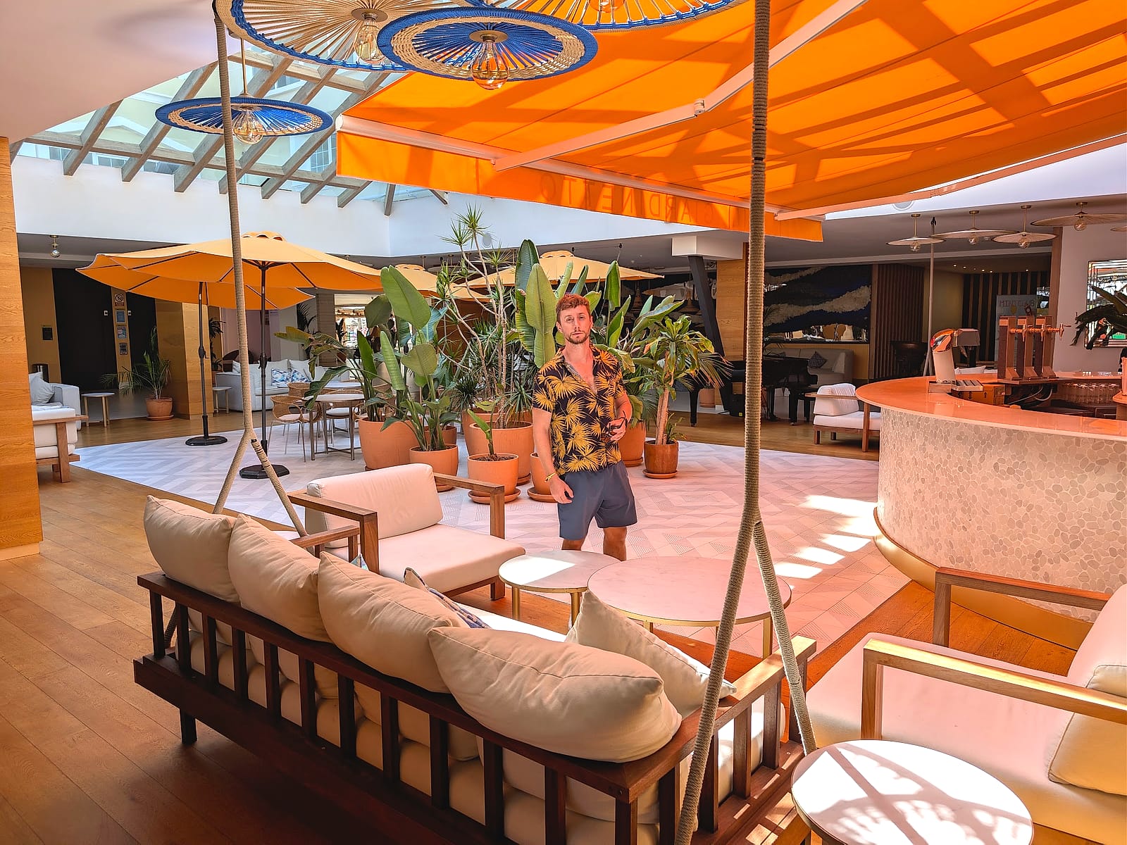 Javier Sobrino en el salón del vestíbulo del Mediterráneo Bay, con sofás columpio y toldo naranja