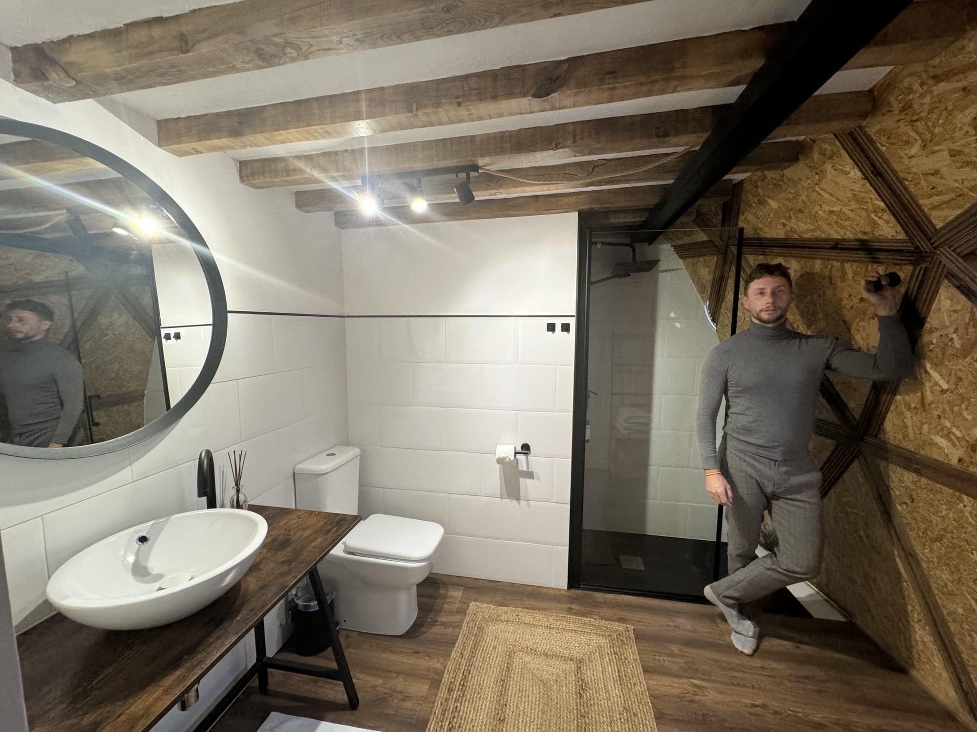 Baño del domo de Miradomos con espejo redondo, ducha y vigas de madera