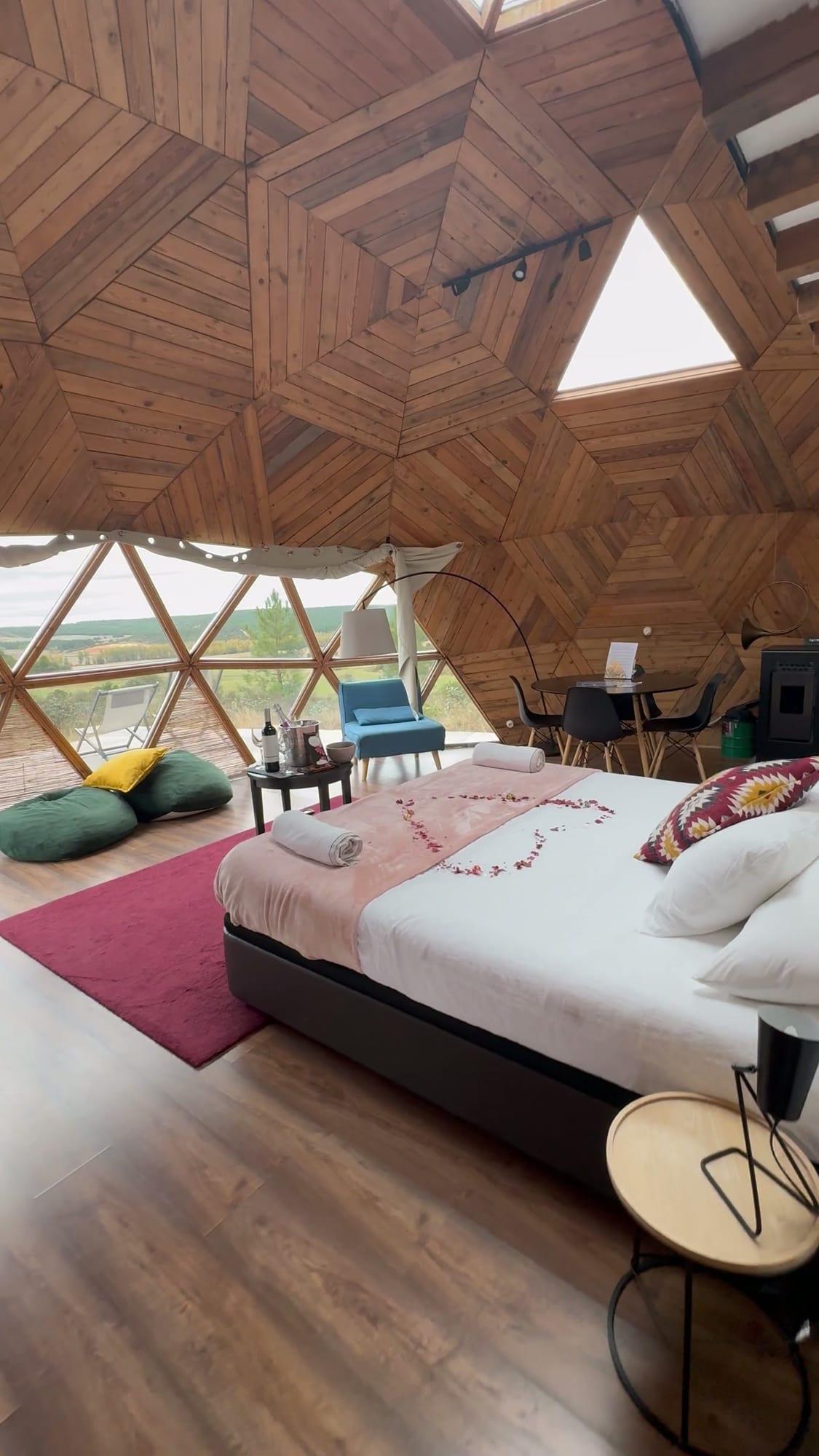 Domo de madera de Miradomos con la cama decorada con pétalos y el ventanal al campo de Soria