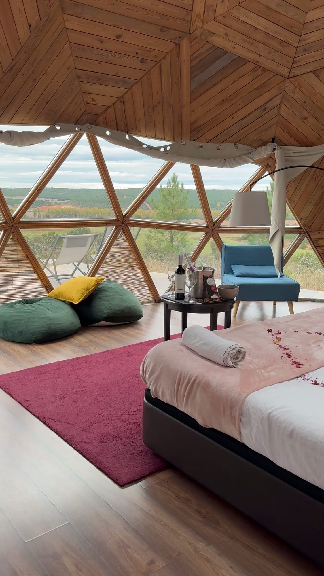 Ventanal geodésico del domo de Miradomos con pufs, sillón y vistas al campo