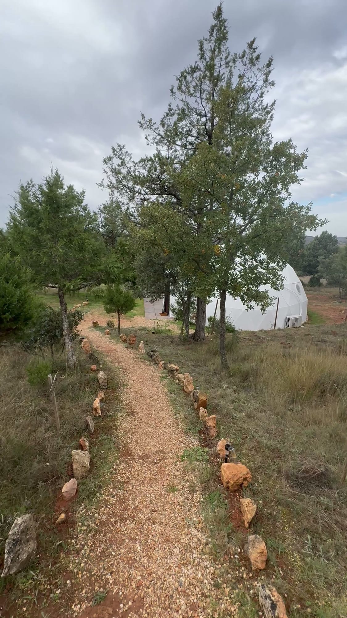 Sendero bordeado de piedras hacia un domo blanco de Miradomos