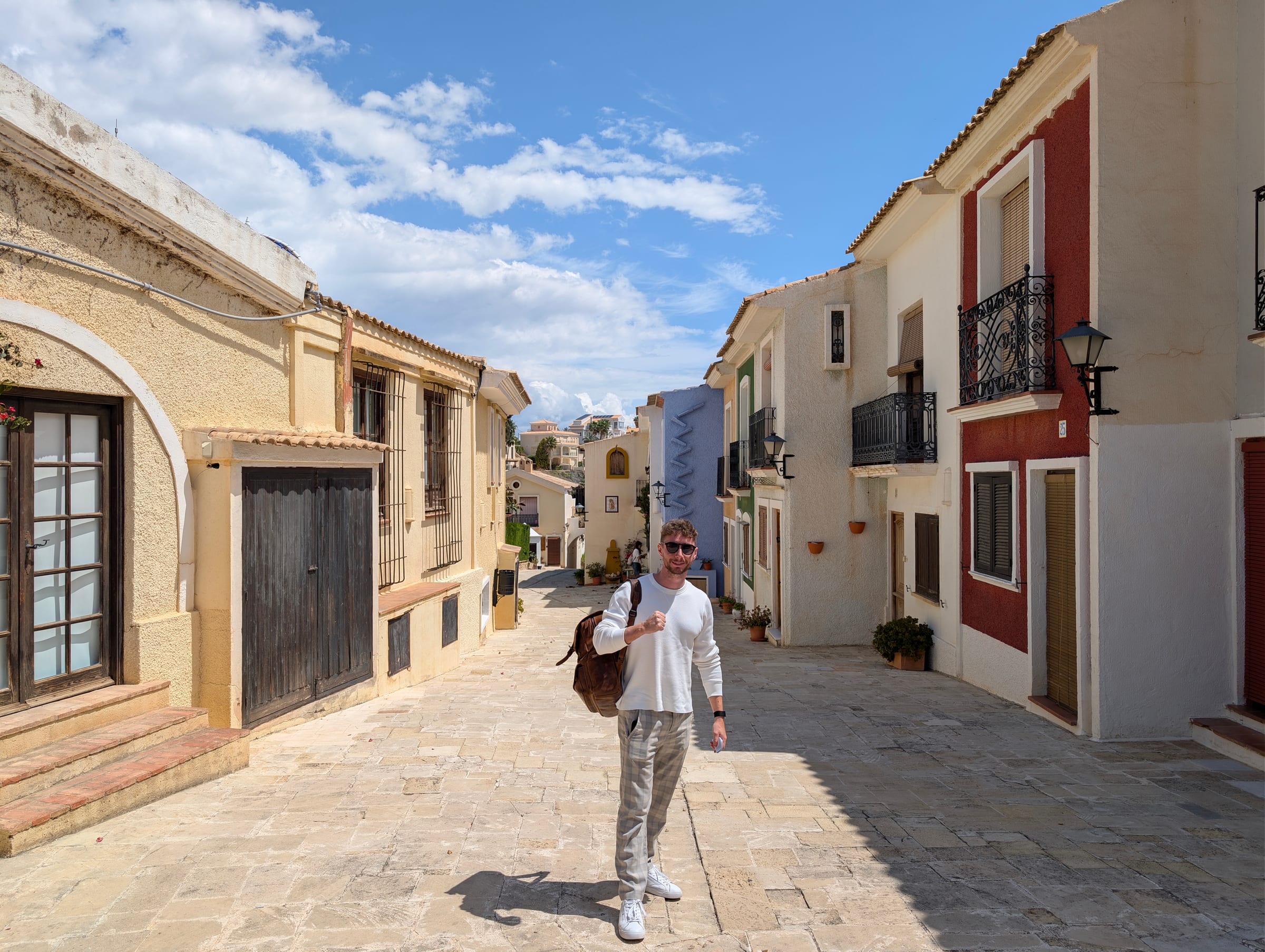 Javier Sobrino paseando por una calle empedrada del Occidental Pueblo Acantilado, entre casas encaladas y de colores
