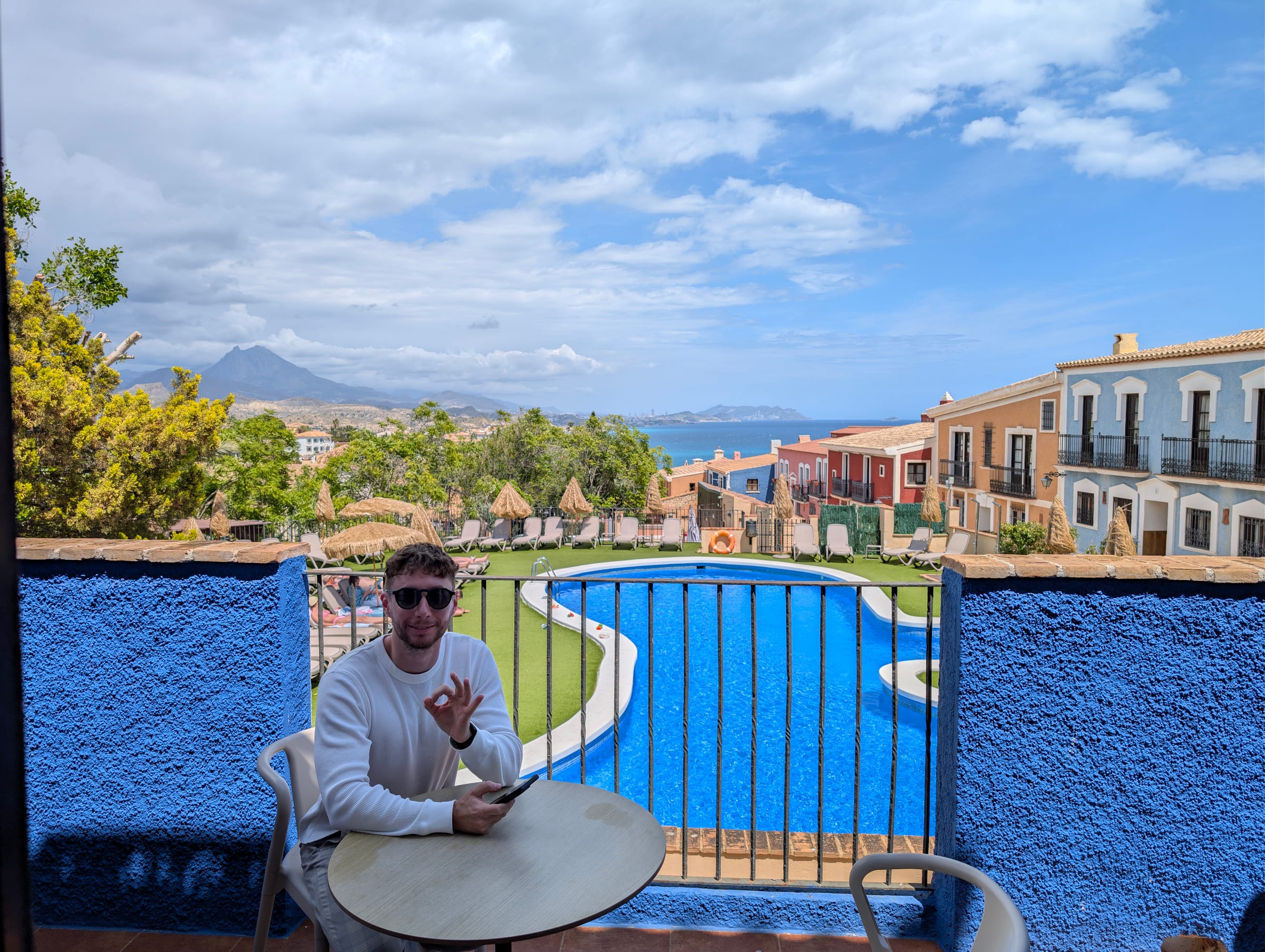 Javier Sobrino en la terraza de su habitación del Occidental Pueblo Acantilado, con la piscina, el pueblo y el mar detrás