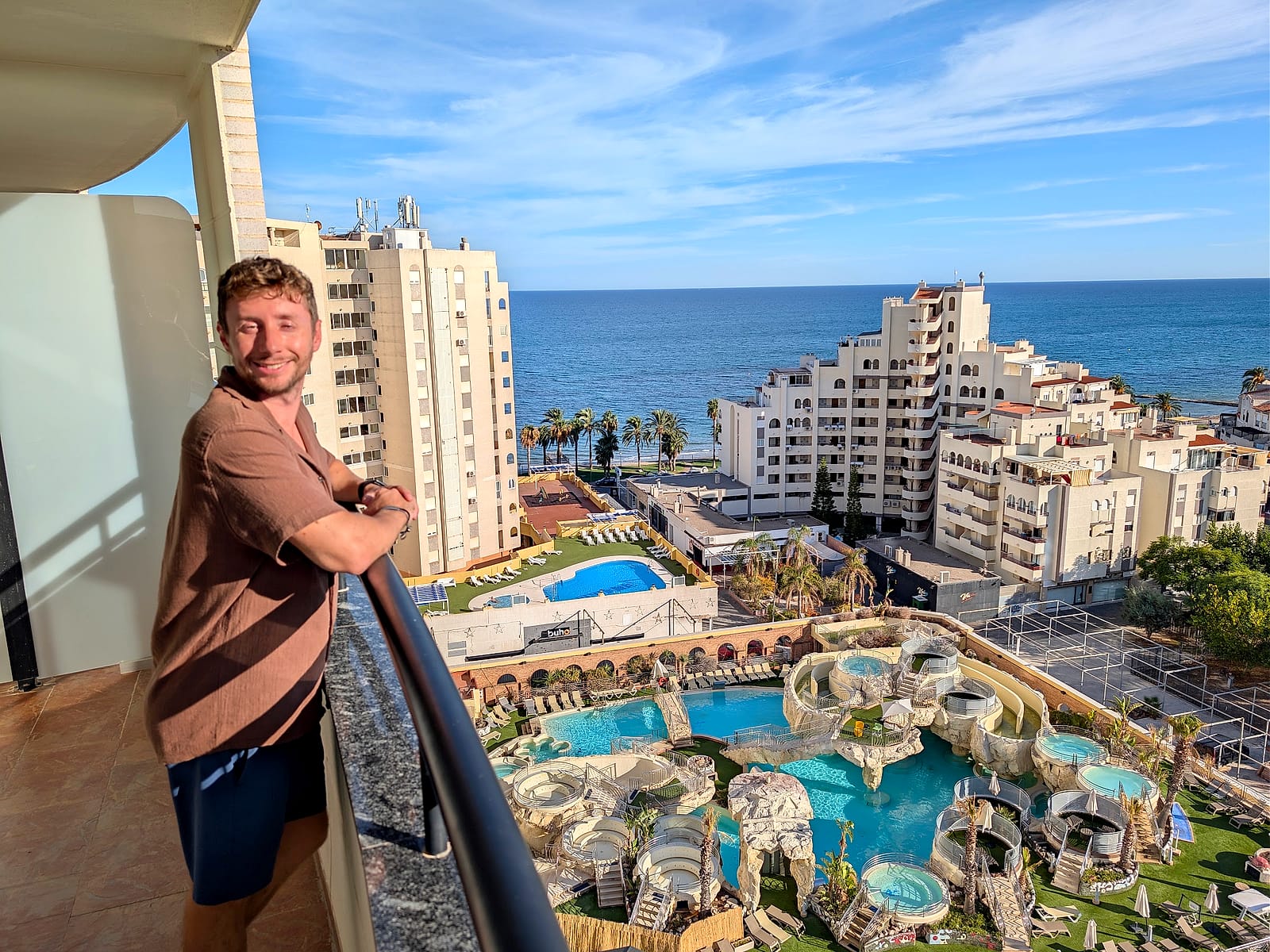 Javier Sobrino en el balcón de su habitación del Pontiana Thalasso, con el thalasso exterior abajo y el mar detrás