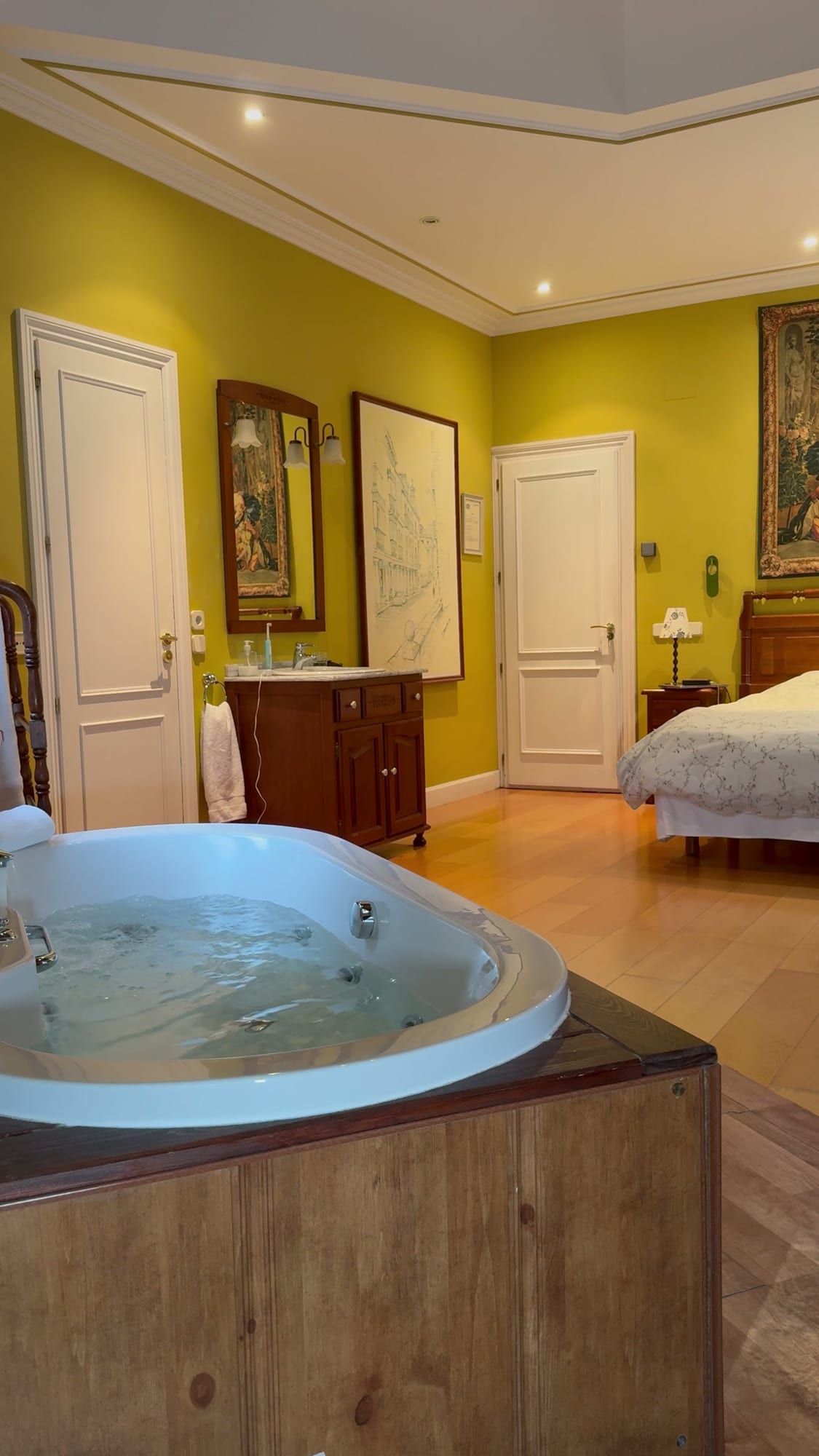 Bañera de hidromasaje llena en la suite del Hotel Don Jaime, con la cama al fondo