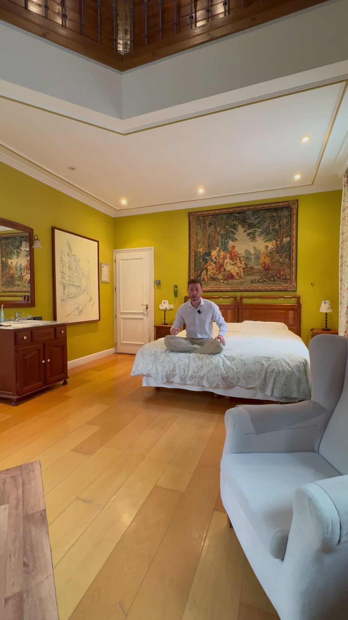 Javier Sobrino sentado en la cama de la suite del Hotel Don Jaime, bajo un tapiz