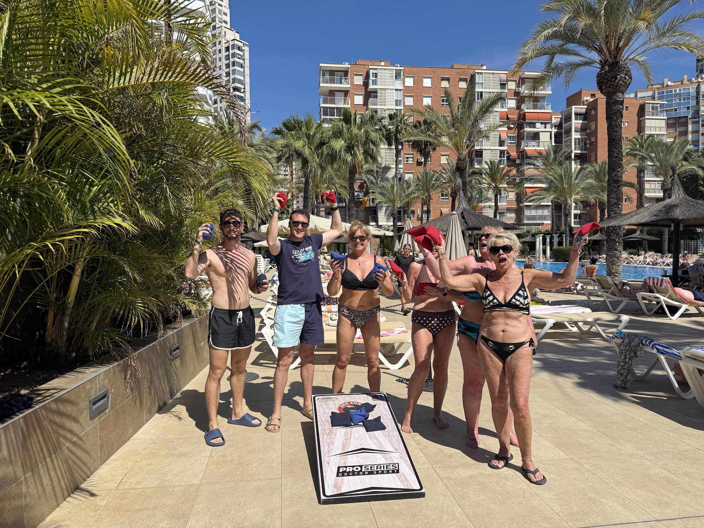 Grupo de huéspedes celebrando en el juego de cornhole de la animación del Sol Pelícanos Ocas