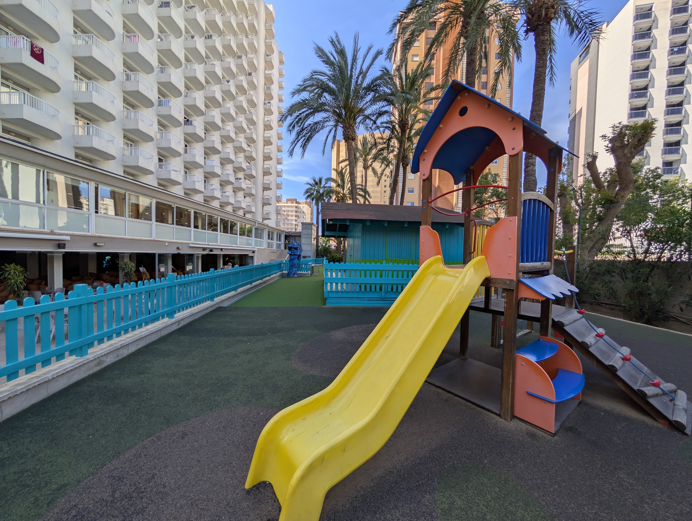 Parque infantil con tobogán amarillo junto al edificio del Sol Pelícanos Ocas