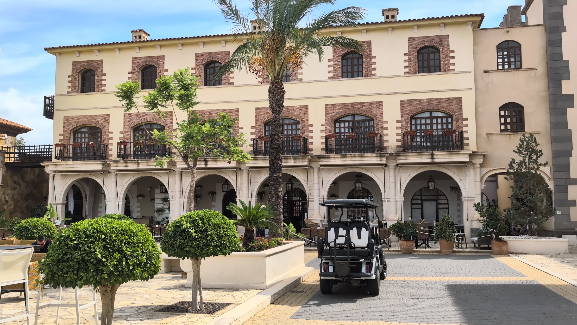 Fachada con arcos, palmera y carrito de golf en el Meliá Villaitana