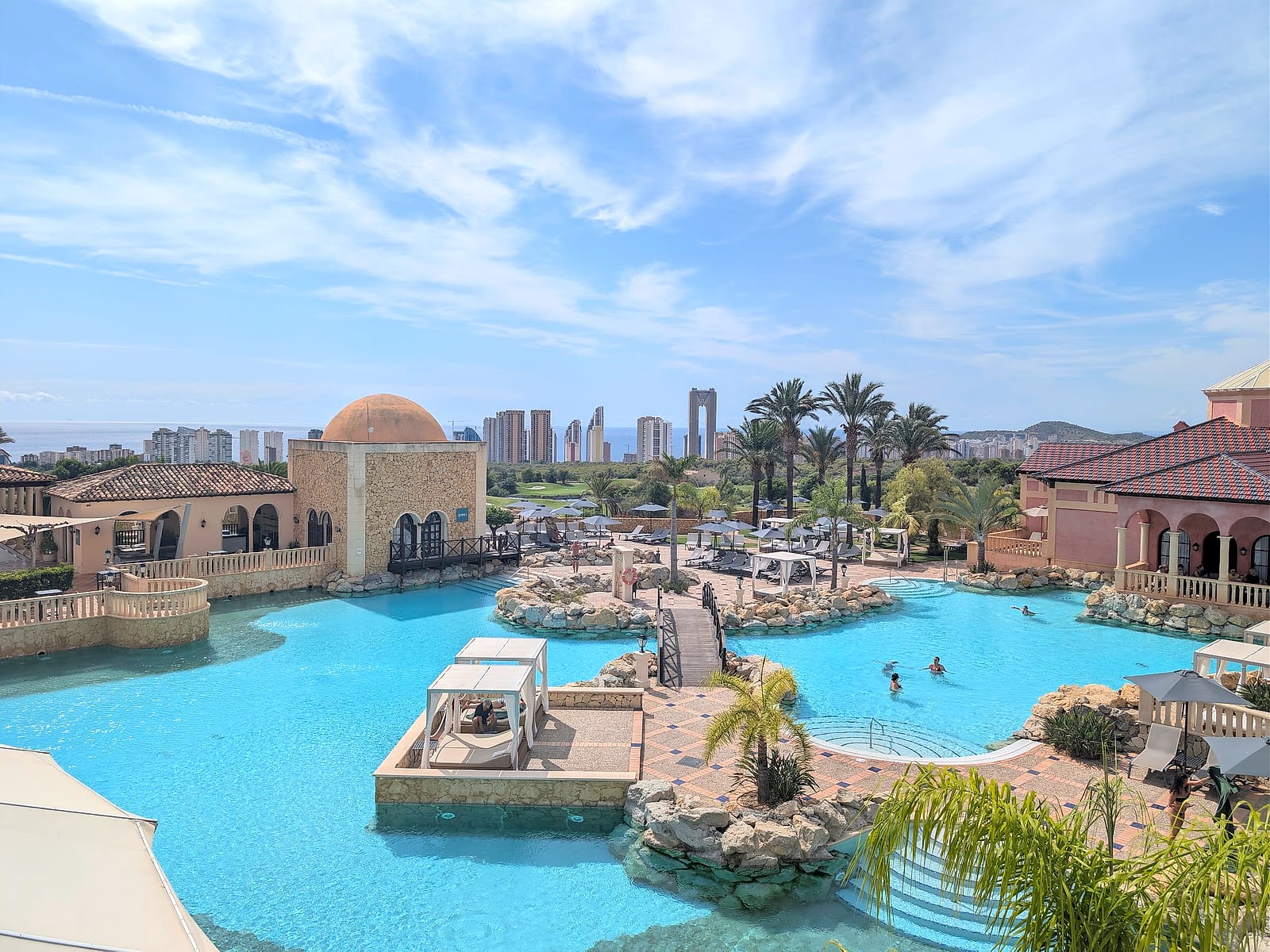 La piscina de The Level, con puentes, camas balinesas y el skyline de Benidorm al fondo