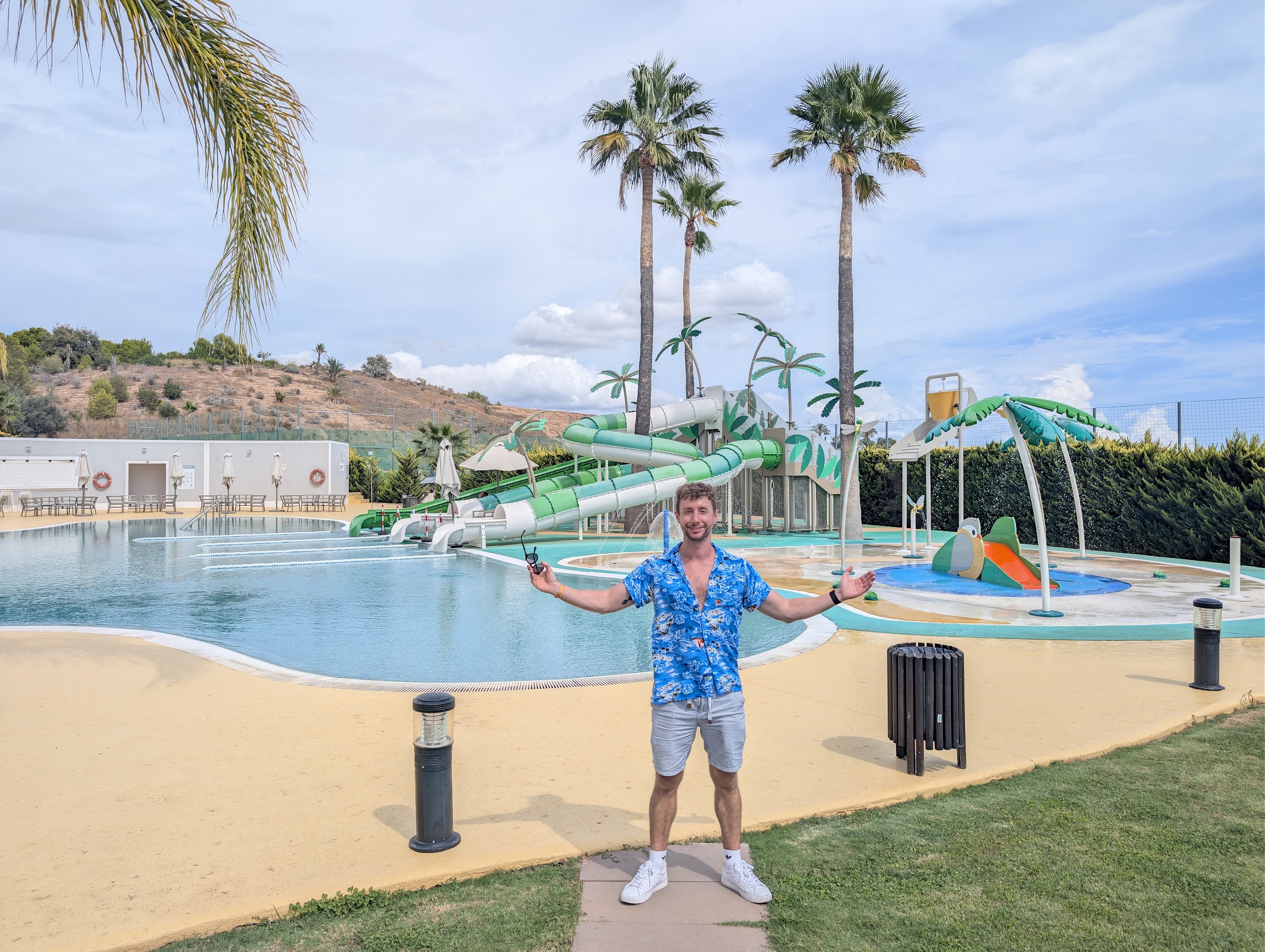 Javier Sobrino con camisa hawaiana con los brazos abiertos ante los toboganes del Meliá Villaitana